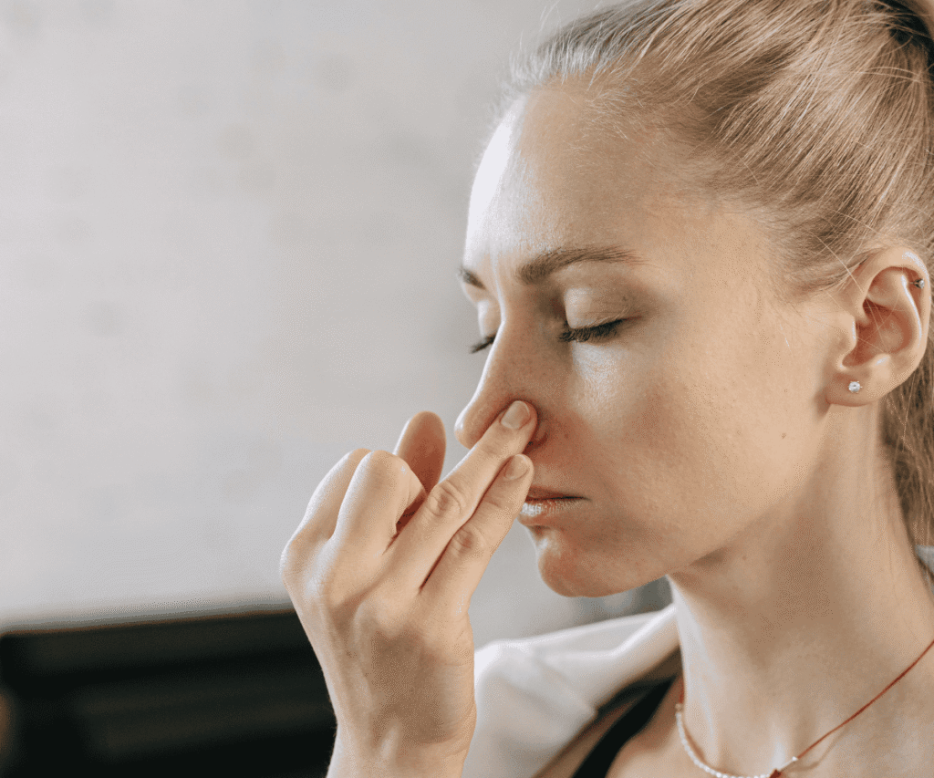 Woman practicing Nadi Shodhana Pranayama with eyes closed, using right hand to close one nostril