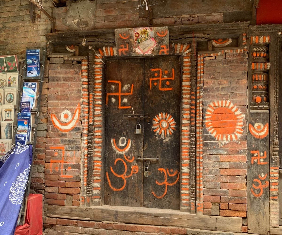 Ancient wooden door in Nepal painted with vibrant red and orange religious symbols
