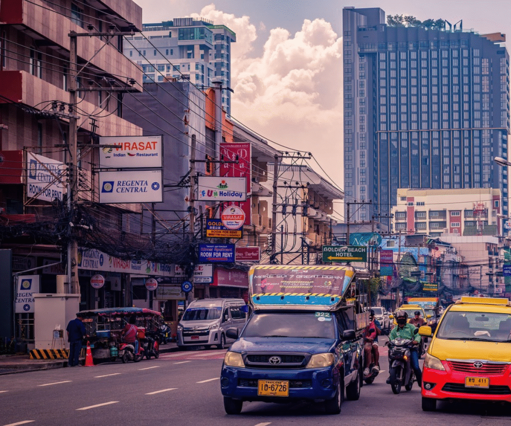 Busy street in Pattaya with colorful signs, motorbikes, and songthaews