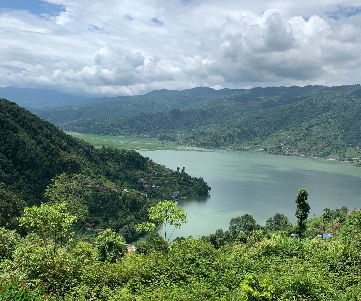 Overhead view of Phewa Lake surrounded by green hills and scattered homes