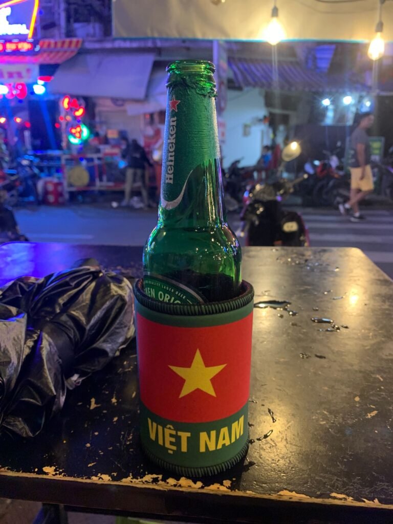 Cold Heineken beer in a Vietnam flag sleeve on a street table at night