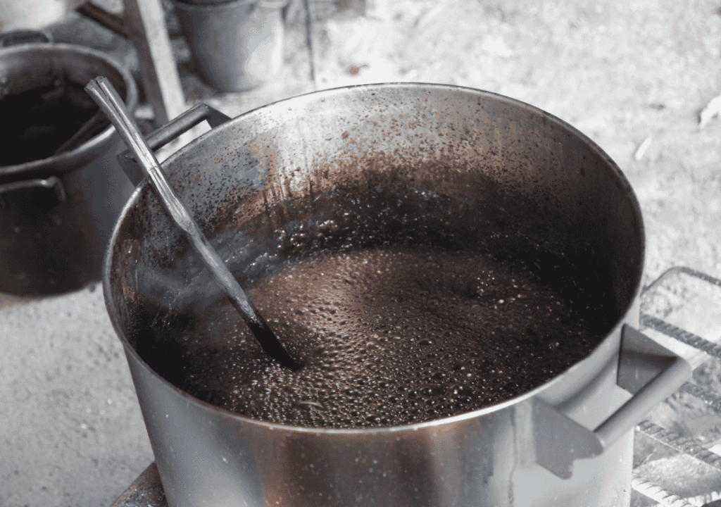 Close-up of a large pot of ayahuasca brewing over heat, illustrating the preparation process and physical dangers of ayahuasca.