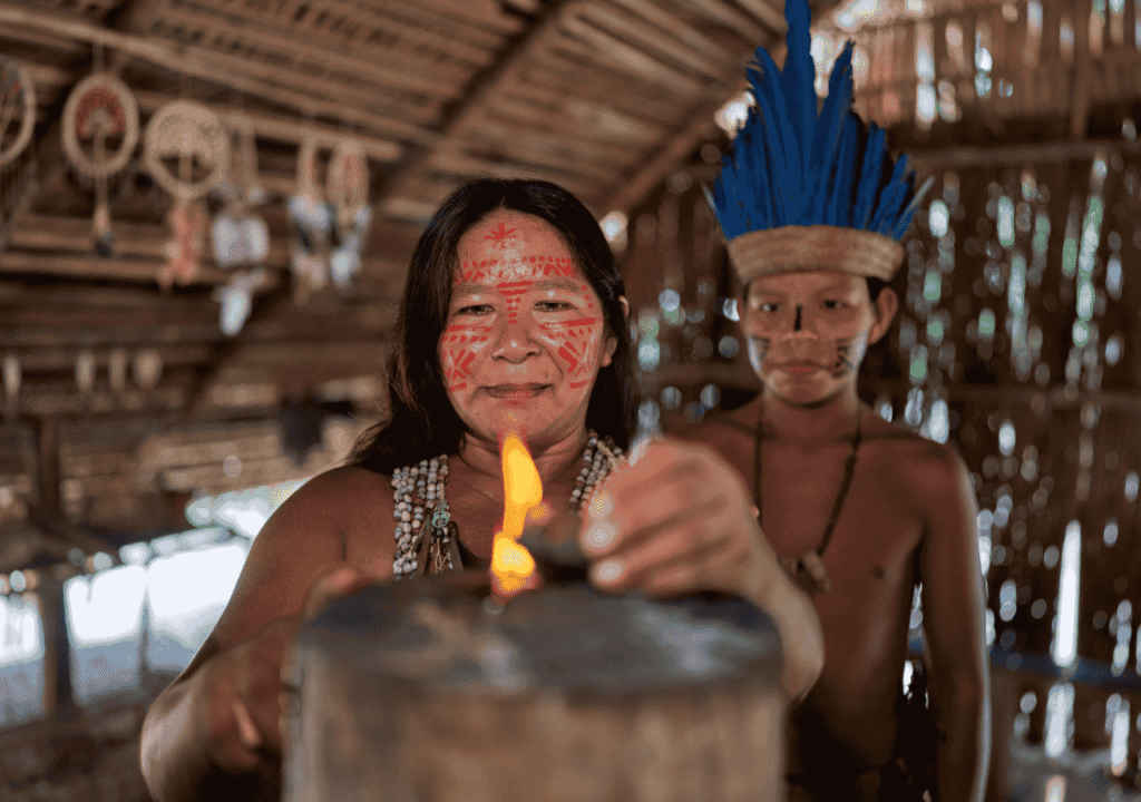 Indigenous woman and child in traditional attire and face paint participating in a ceremonial setting, representing authentic cultural roots before the commercialization and dangers of ayahuasca tourism.
