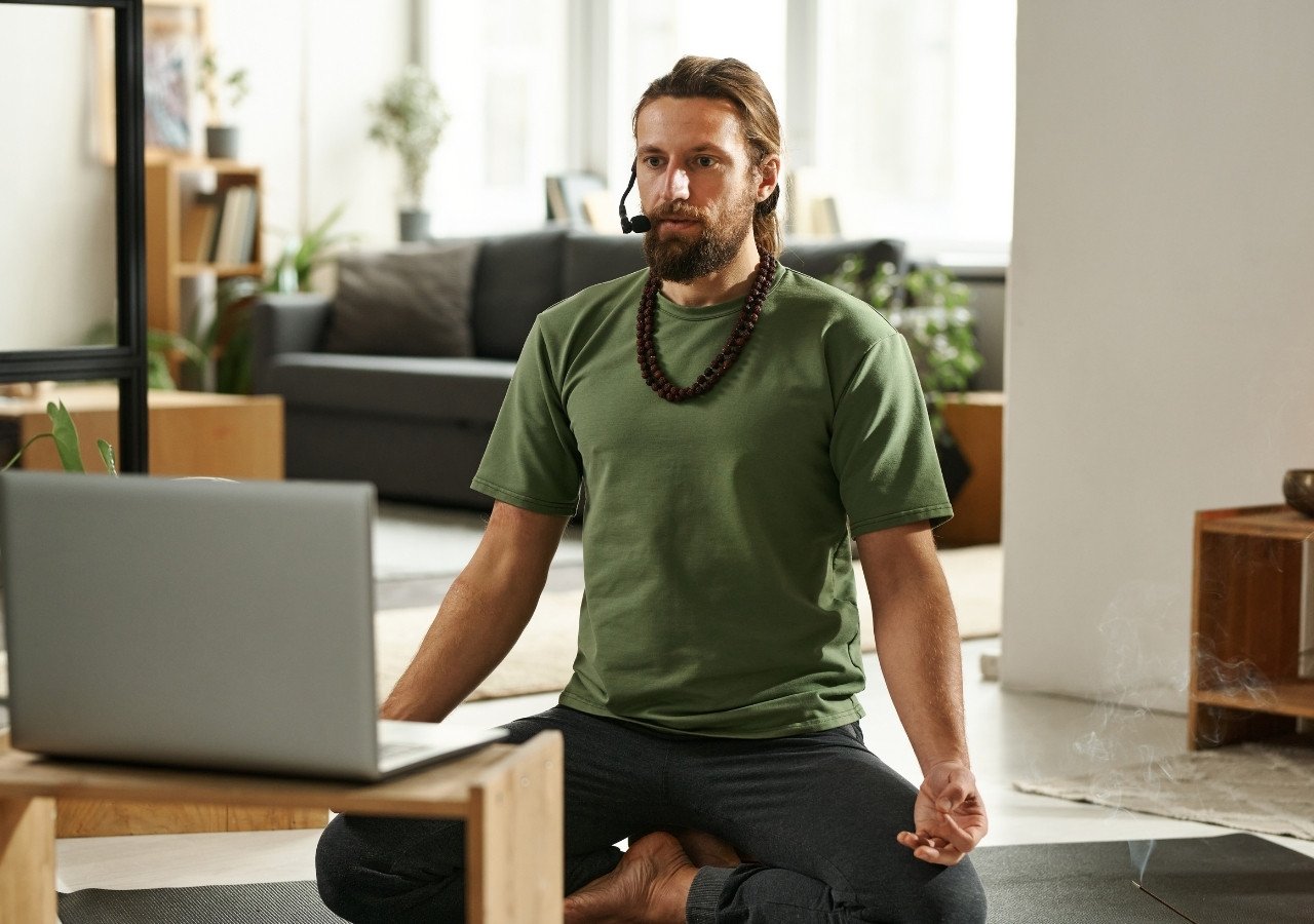 Yoga instructor attending virtual teacher training with laptop and headset