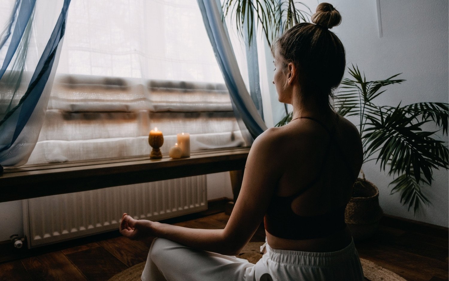 rekindle-your-love-for-yoga-meditation-candles Woman meditating indoors with candles, reconnecting with her yoga practice.