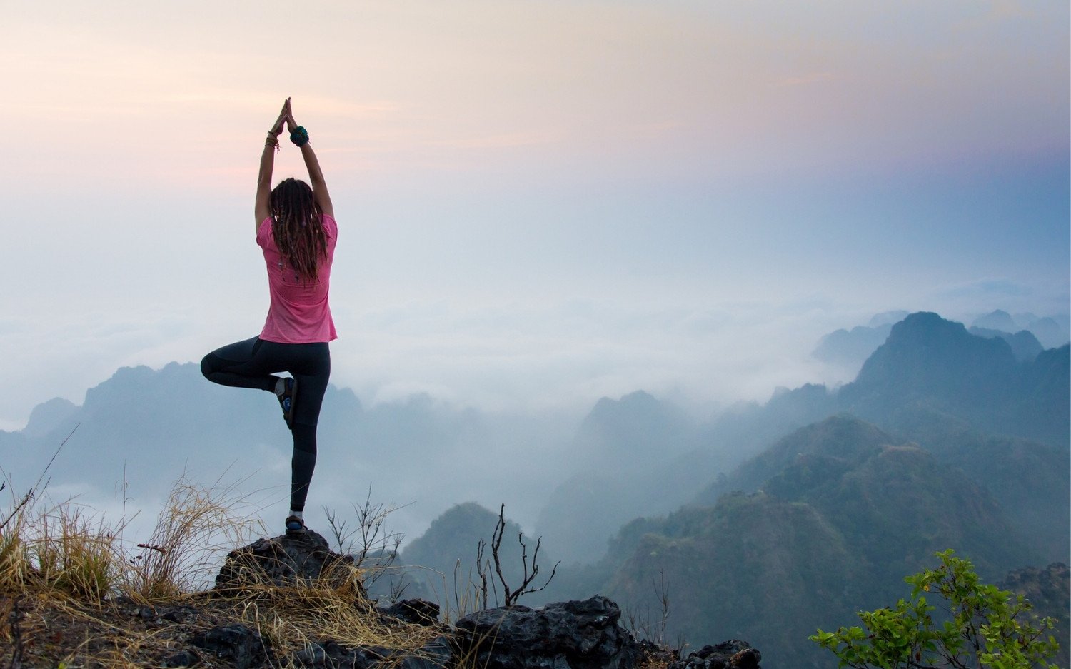 rekindle-your-love-for-yoga-tree-pose-mountain Woman practicing tree pose on a mountain at sunrise.