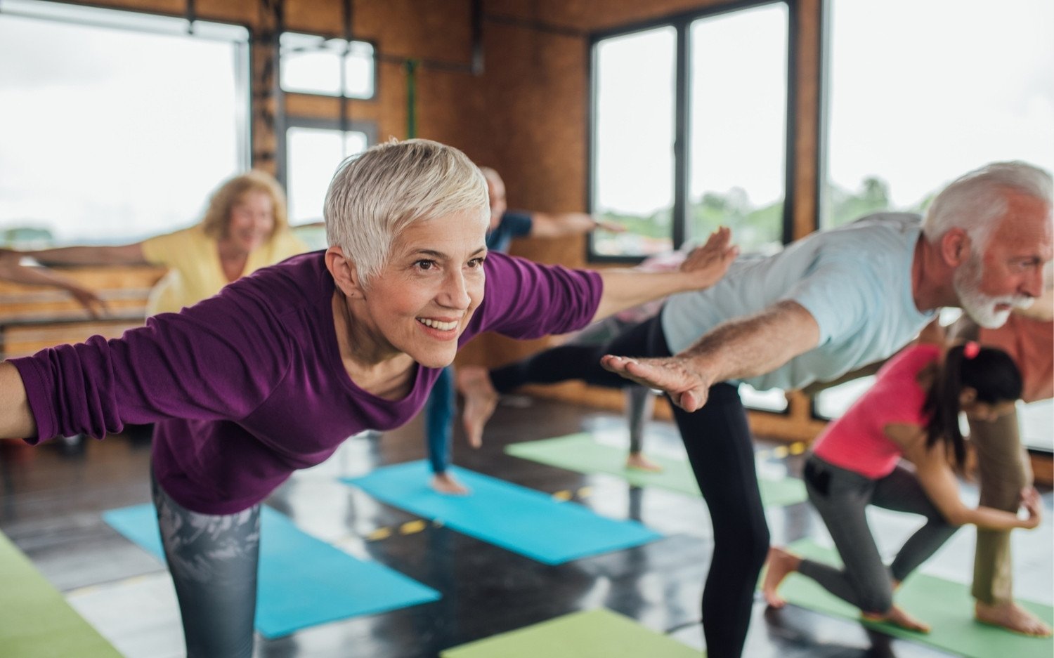 yoga-class-balance-pose-support-network Yoga teacher guiding balance pose in a supportive studio group
