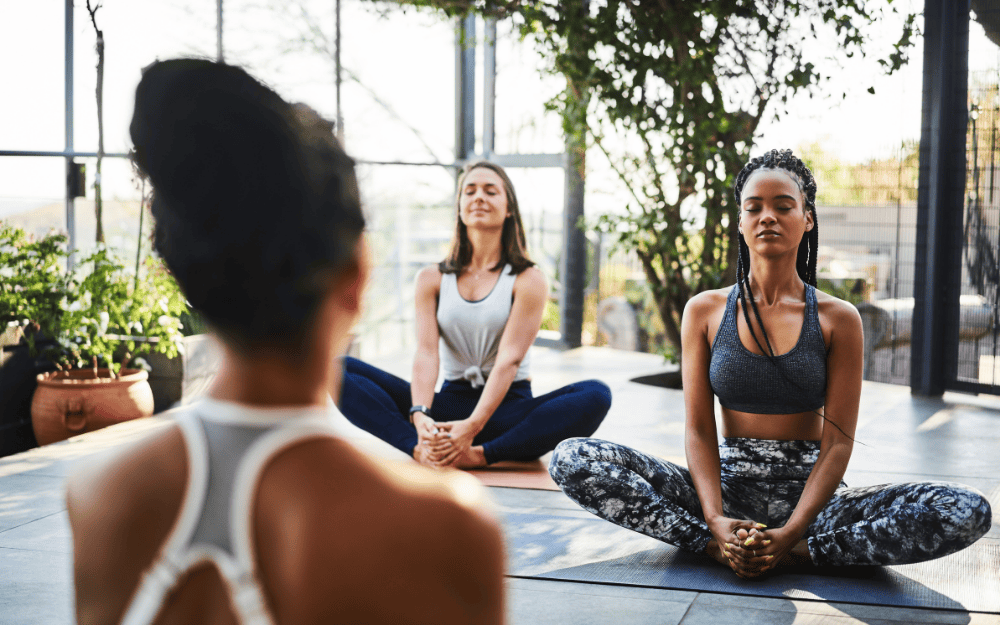 yoga-class-seated-meditation-outdoor-studio Yoga students in seated meditation during class in an outdoor-style studio