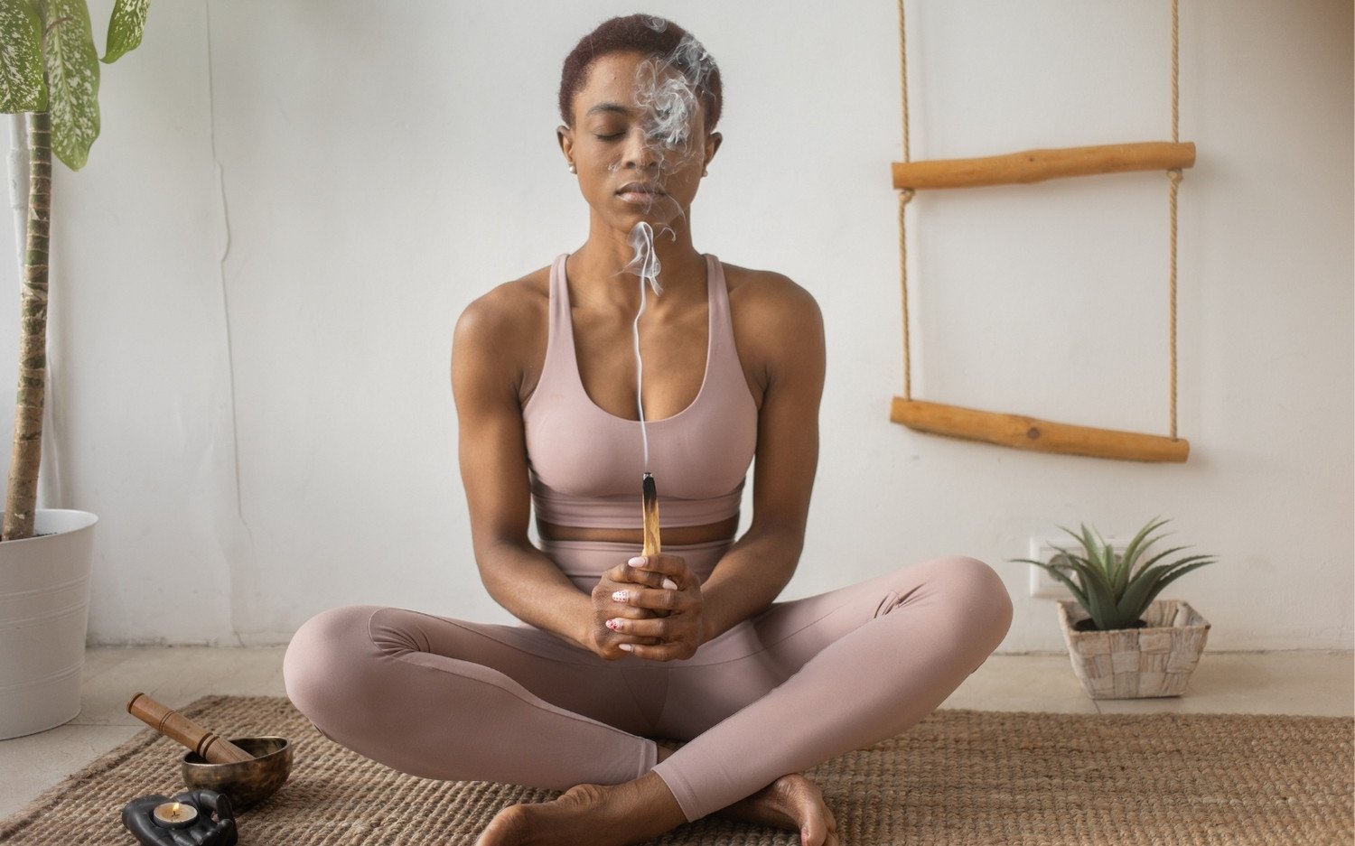 yoga-student-meditation-checklist Yoga student sitting cross-legged in meditation holding incense stick