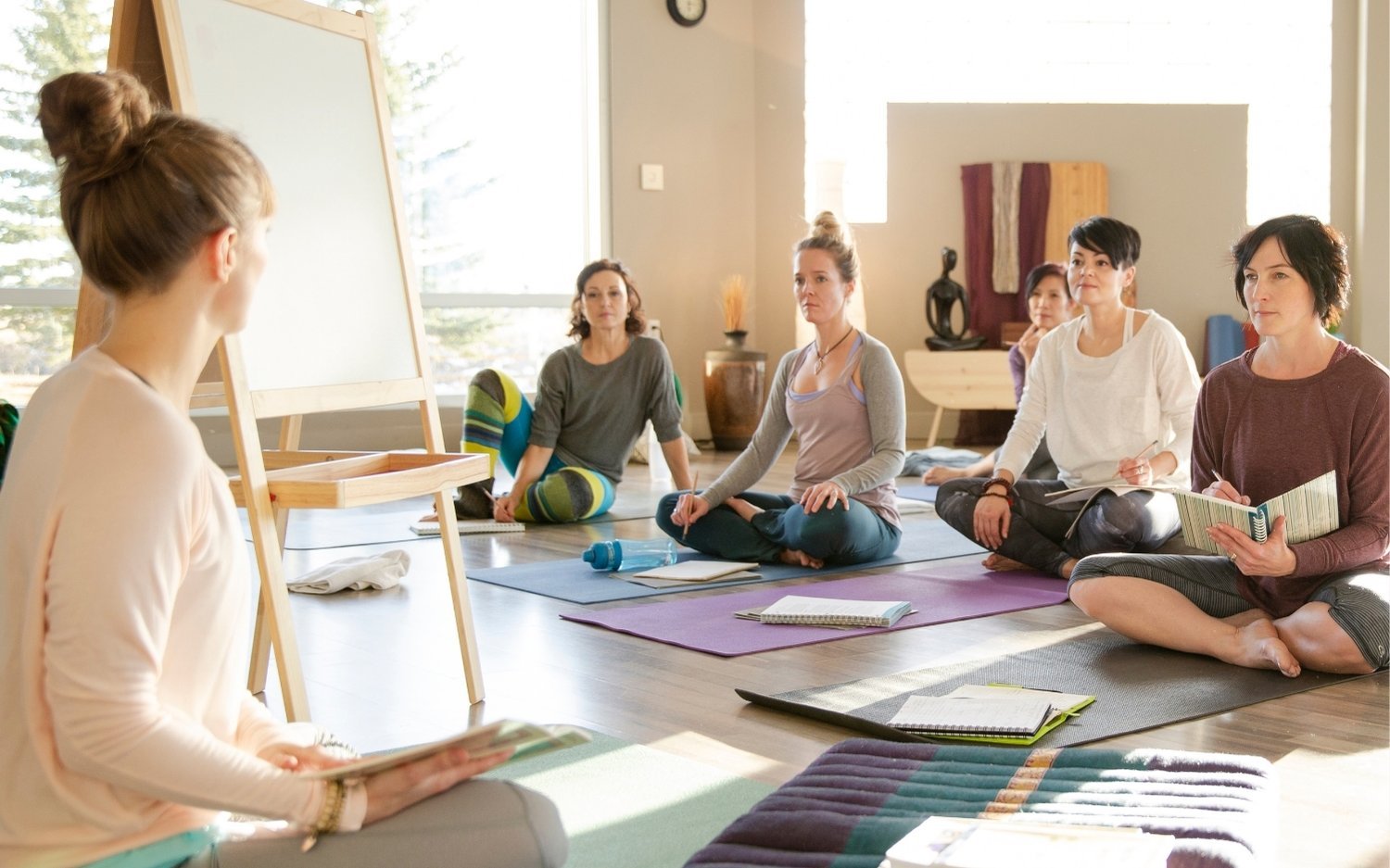 Yoga teacher training students taking notes during classroom workshop