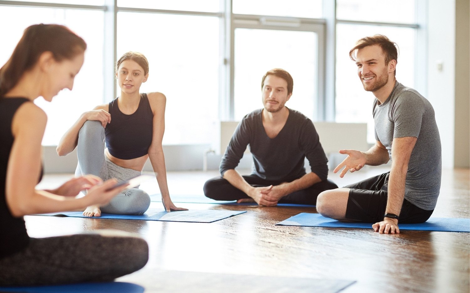 yoga-teacher-training-group-discussion Yoga teacher trainees sitting on mats in a bright studio, discussing 5 fears every yoga teacher trainee has