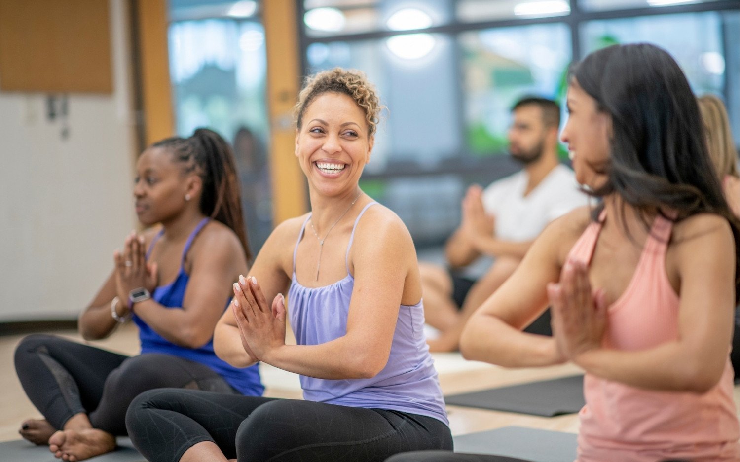 yoga-trainees-smiling-class-community-support Yoga teacher training students smiling and talking during class, building community