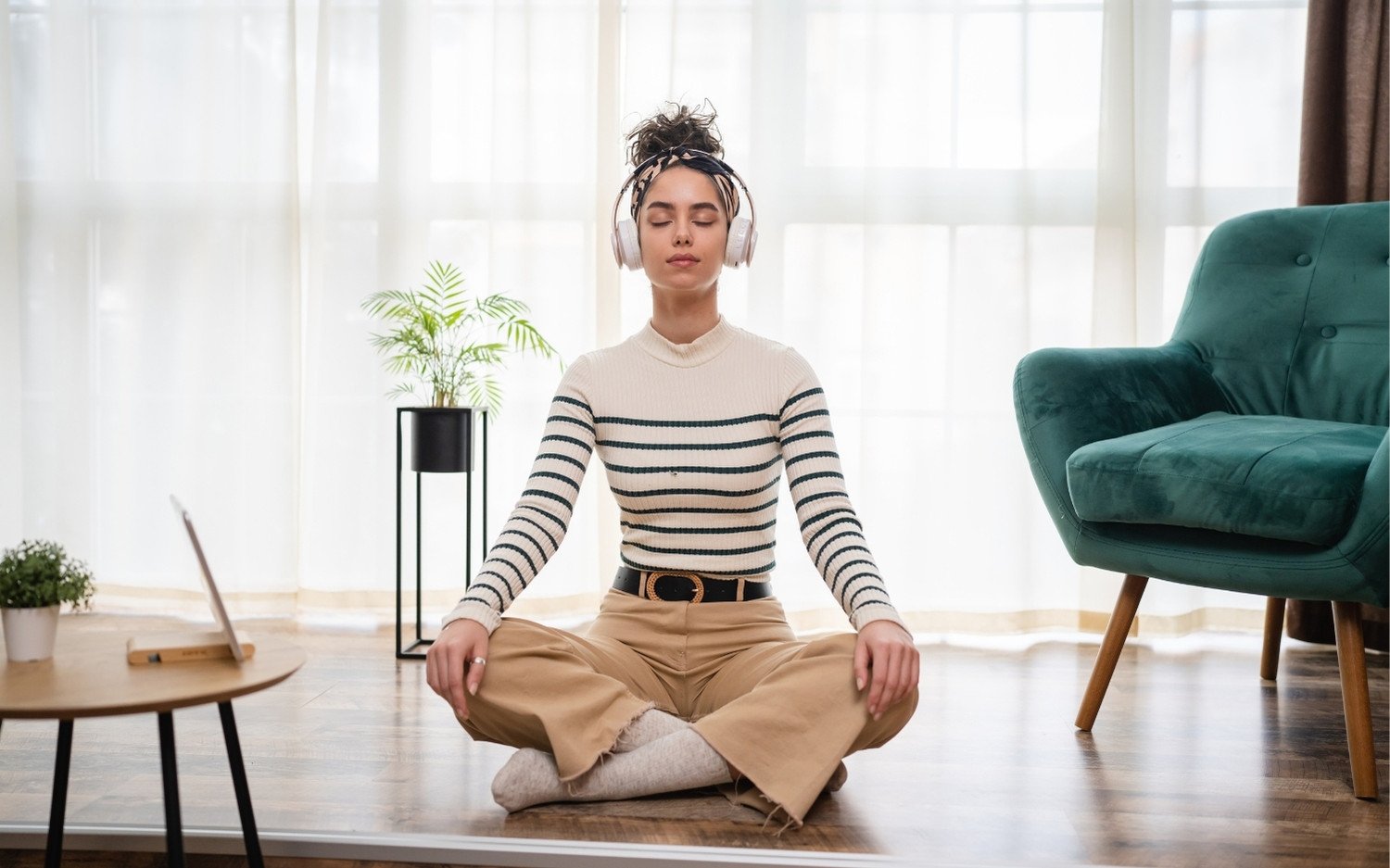 ytt-self-care-mindfulness-practice Yoga teacher trainee practicing seated meditation with headphones for mental balance