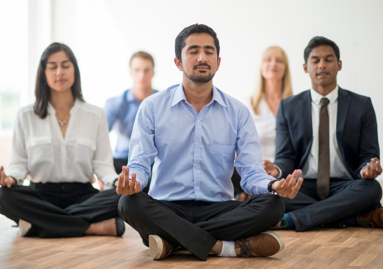 Business professionals practicing meditation during a corporate yoga session