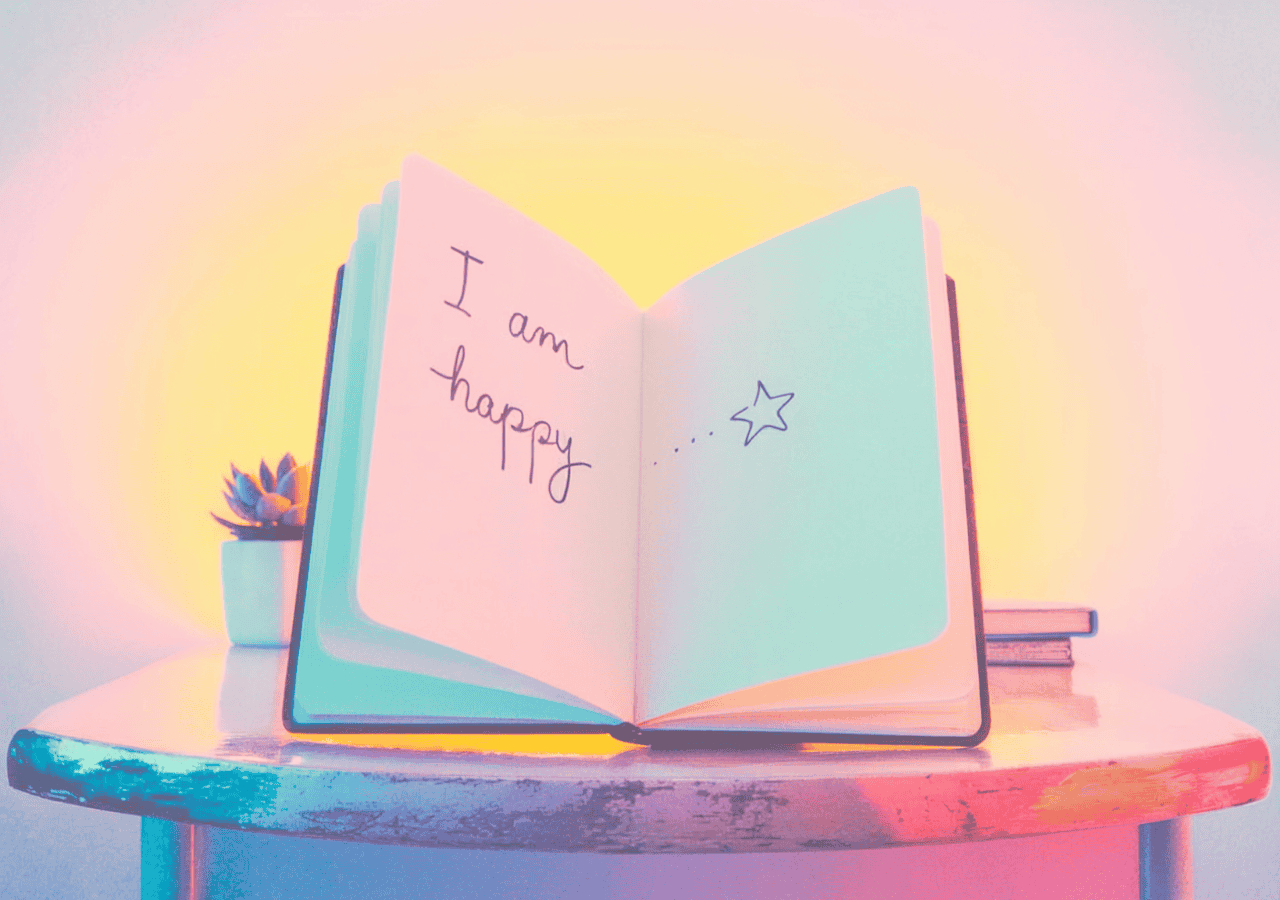 Open notebook on a table with the phrase “I am happy” written inside, representing daily affirmation practice