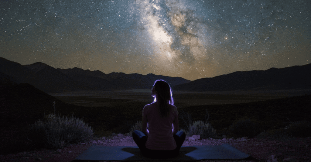 Woman sitting in meditation facing the Milky Way night sky